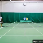 Home 21 배드민턴 초보자를 위한 경기 매너 - A vibrant scene of a friendly badminton match in a well-lit indoor court, featuring diverse Arab adu...